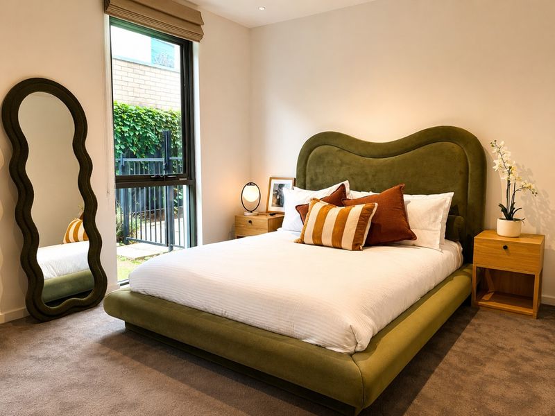 Green upholstered queen bed in a bright guest bedroom